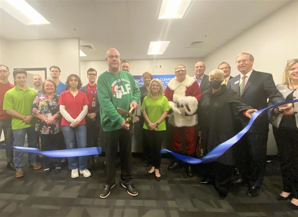 James Clemens principal Dr. Brian Clayton in front of crowd cutting ribbon. Students behind him in the bank branch 